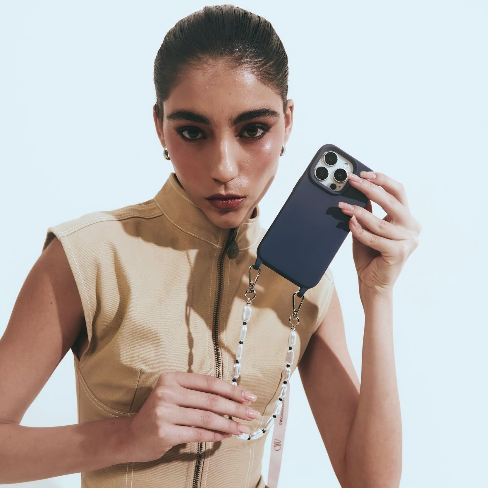Woman holding a phone with a blue case against a light background