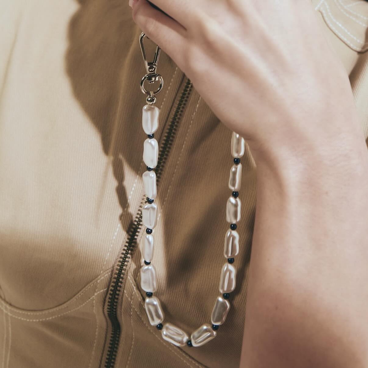 Close-up of a beaded necklace draped over a beige jacket.